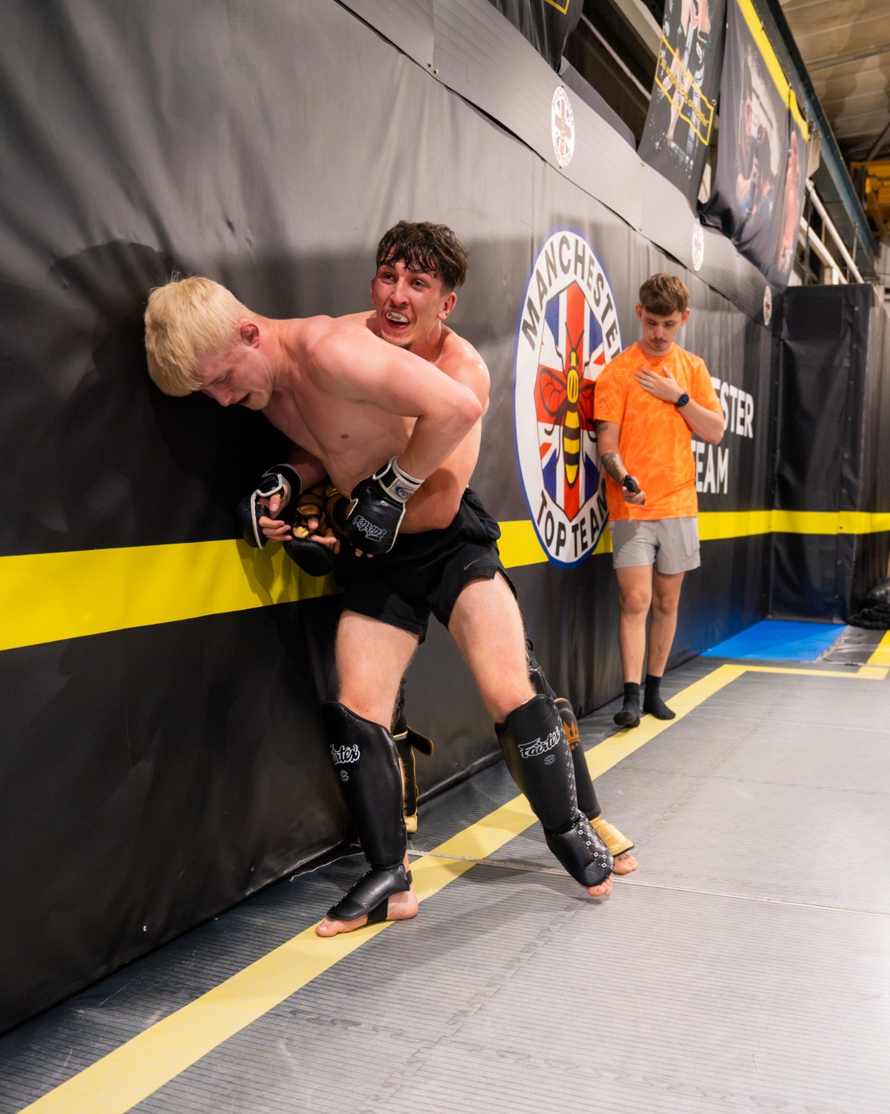 Fighters drilling clinch work against the cage